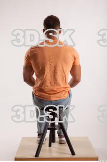 Sitting pose orange thsirt light blue jeans of bodybuilder Harold…